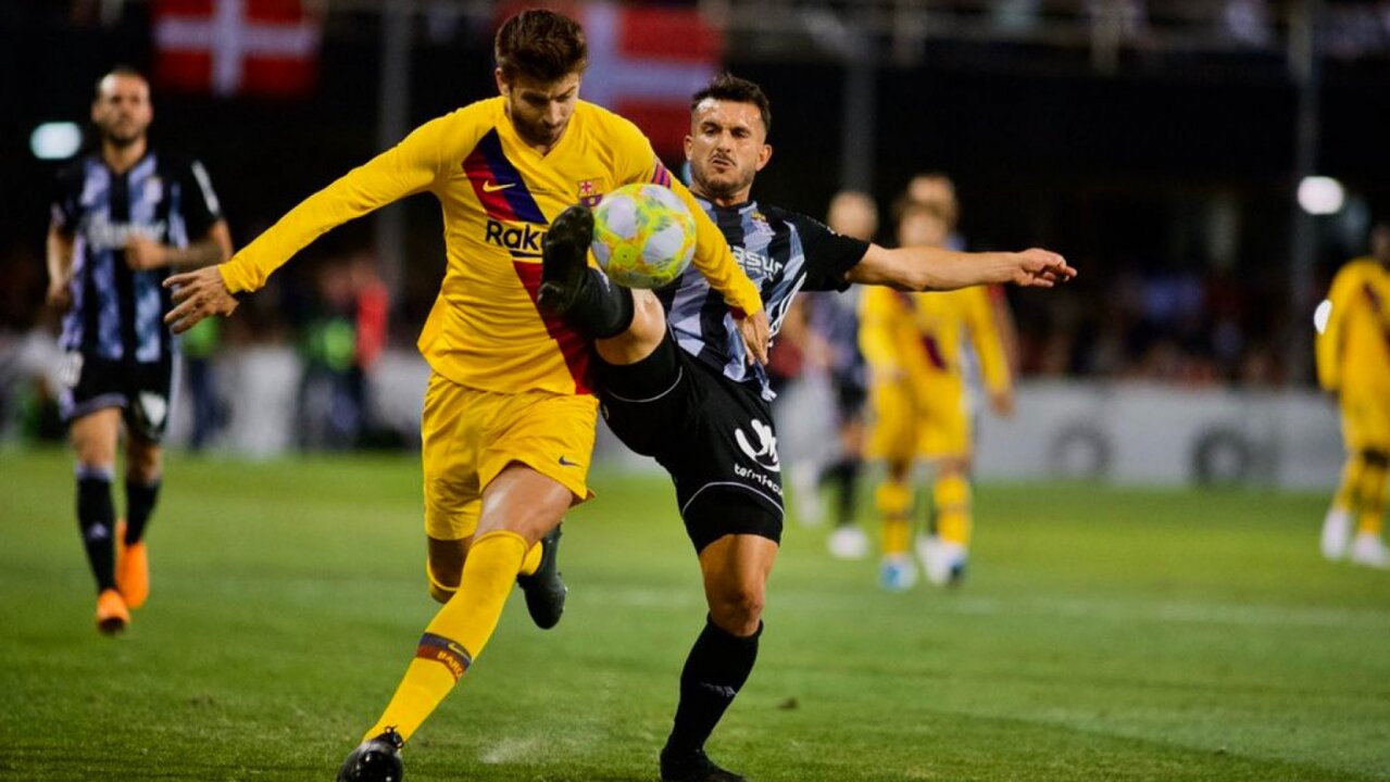 Piqué (FCB) y Elady (FC Cartagena) pugnan por un balón durante el encuentro/Prensa FCC